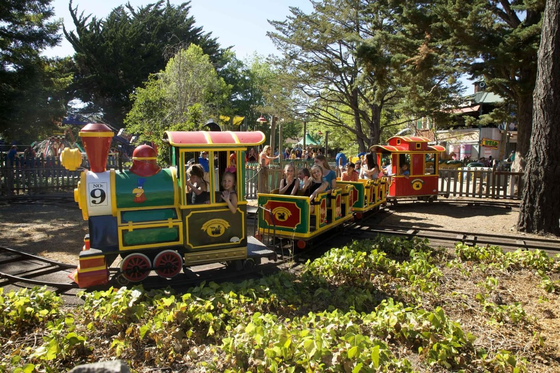 Foghorn's Seaport Railway in motion at Six Flags Discovery Kingdom, with guests smiling for the camera.