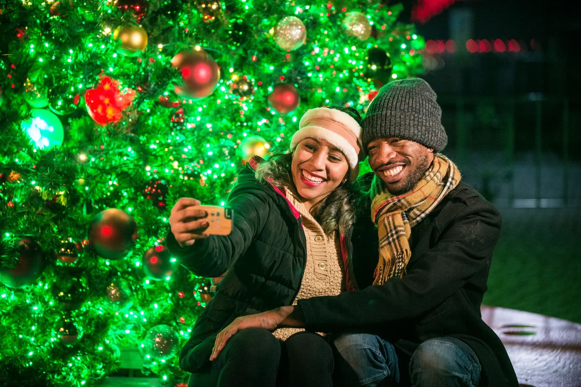 Couple taking a selfie together in front of a Christmas tree