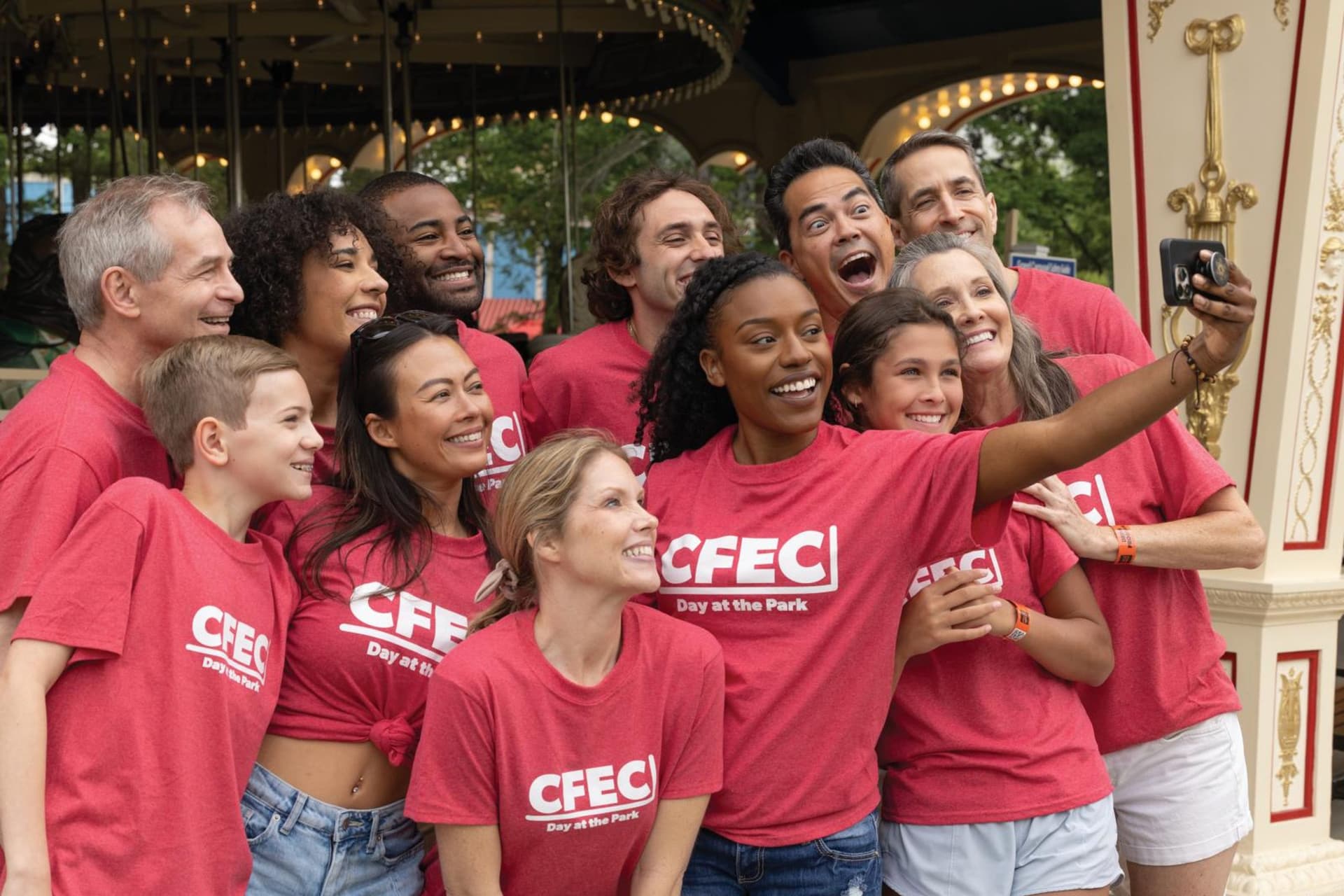 A group of guests posing for a selfie in front of a carousel