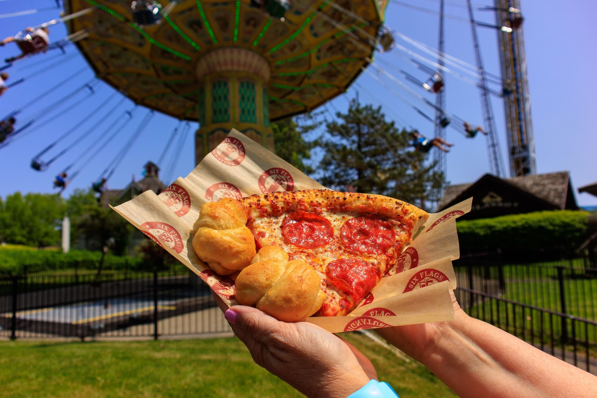 Guests holding a pizza in front of a ride