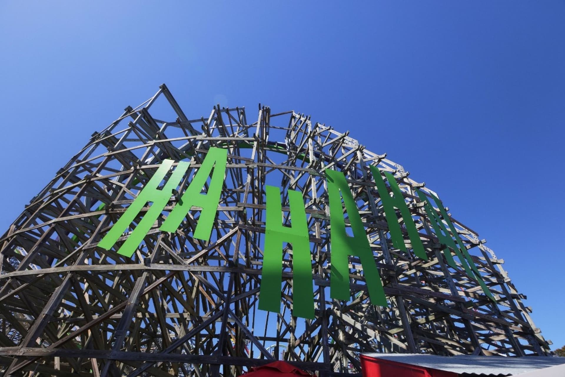 A close-up of THE JOKER's roller coaster structure with the character's infamous "HA HA HA" seen in bold green.