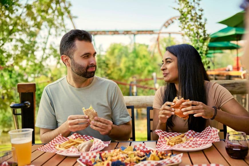 A couple enjoying a meal and loaded nachos at an amusement park.