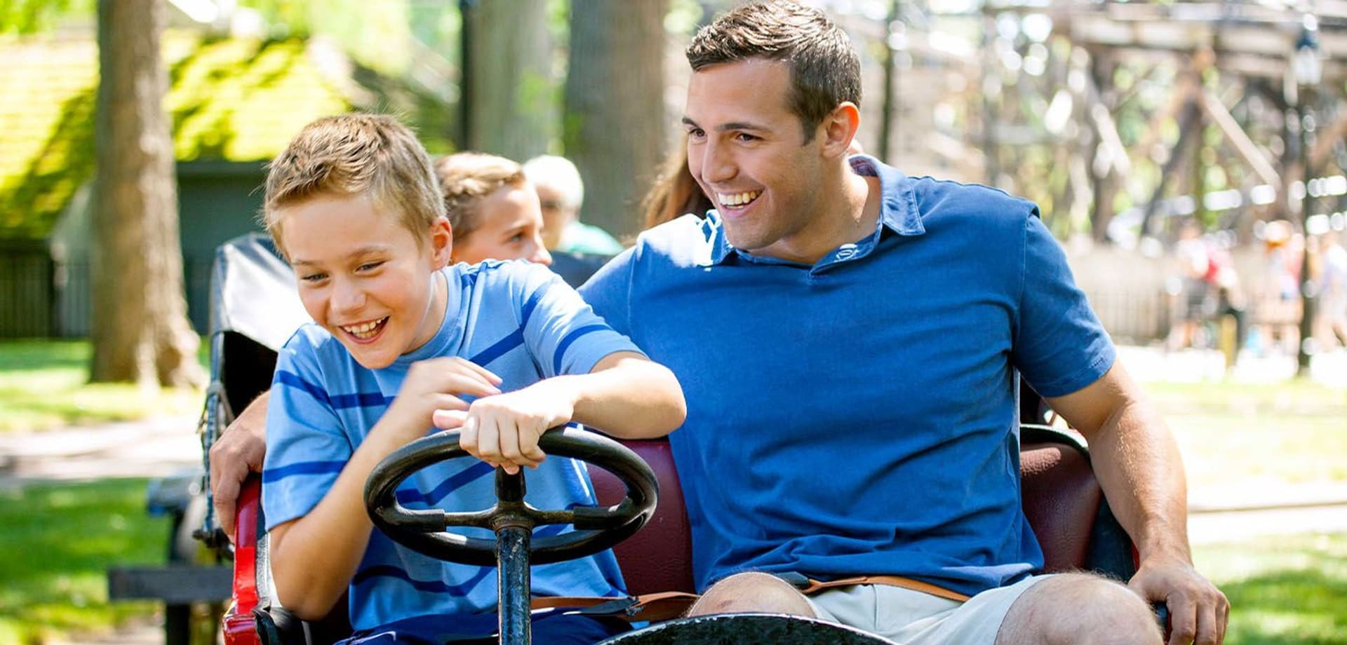 A father and son driving a replica Cadillac Car