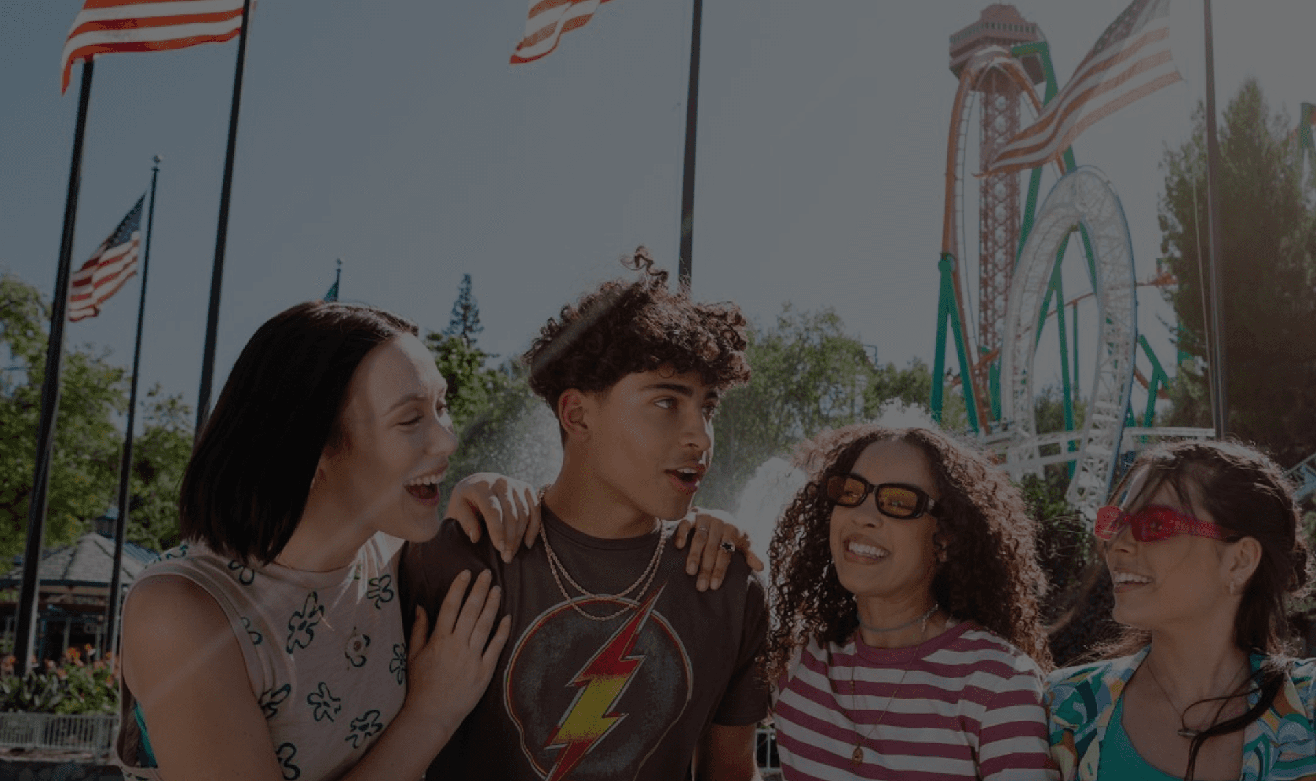Group of friends laughing in front of rollercoasters
